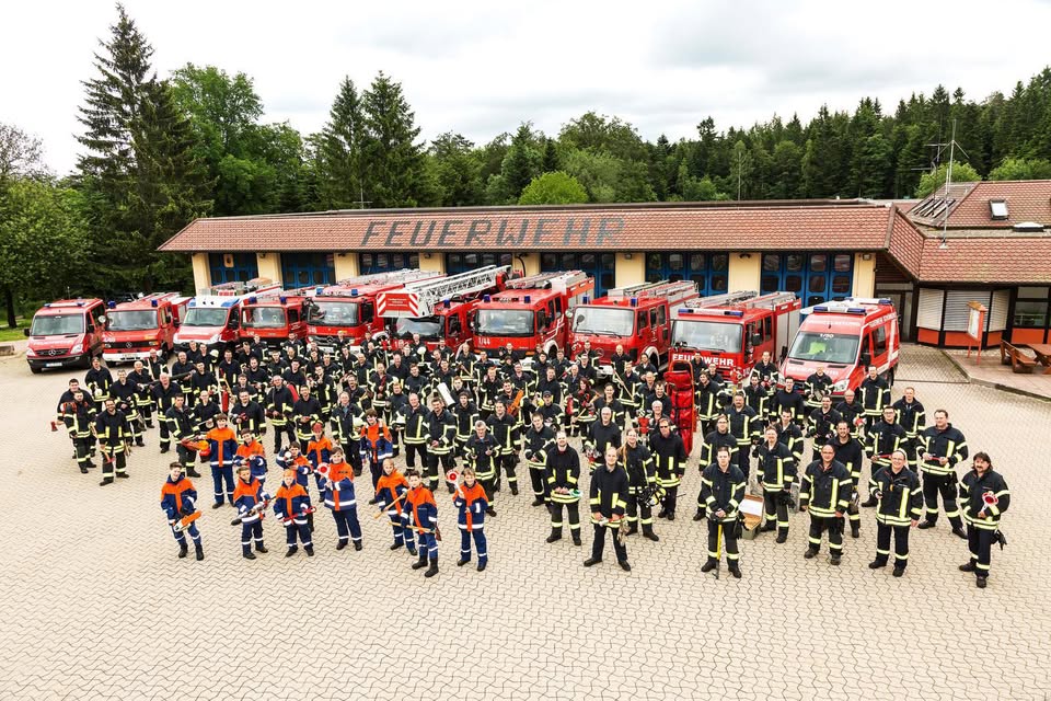 Gruppenfoto der Feuerwehr Schömberg mit Einsatzkräften, Jugendfeuerwehr und Fahrzeugen vor dem Feuerwehrhaus